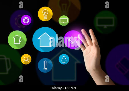 Young woman using futuristic interface of smart home automation on dark background Stock Photo