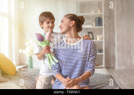 Mother receiving artificial flowers from her cute little son at home Stock Photo