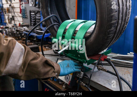 A close-up of a car wheel, a tire is standing on a balancing machine for balancing in an automobile workshop. Work at the tire shop. Stock Photo