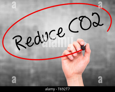 Man Hand writing Reduce CO2 with black marker on visual screen. Stock Photo