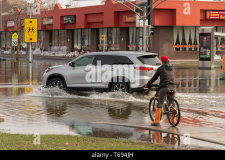 Pierrefonds-Roxboro, Quebec, Canada - 29 April 2019: car driving on a submerged street during spring floods Stock Photo