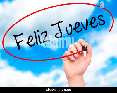 Man Hand writing Feliz Jueves (Happy Thursday In Spanish) with black marker on visual screen. Stock Photo