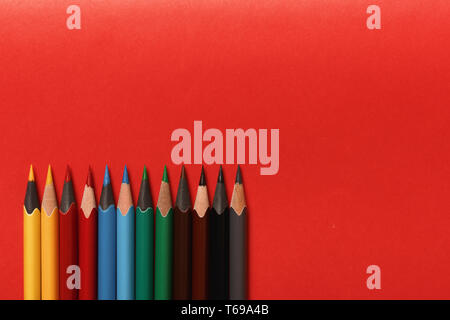 Multicolored pencils lie on a red background Stock Photo