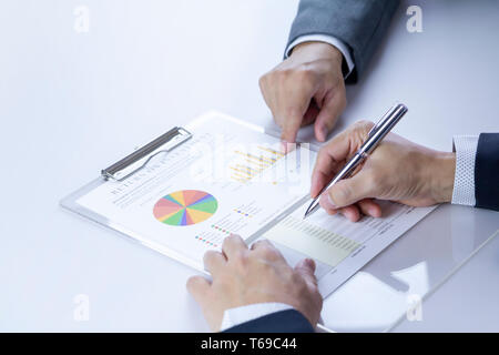 Two businessmen or analysts reviewing financial statement report on Return on Investment, ROI, or investment risk analysis and business performance. Stock Photo