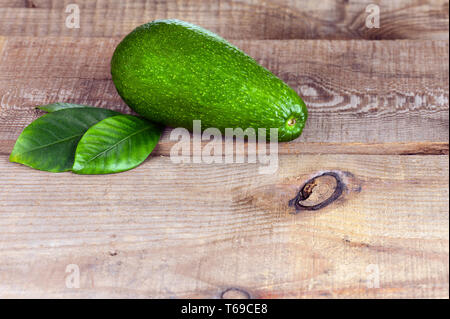 Ripe Green Avocado with Leaves on Wooden Background. Stock Photo