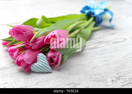 Bouquet of beautiful tulips and small cotton heart on light wooden background Stock Photo