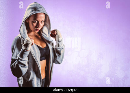 Composite image of portrait of female boxer in hood with fighting stance