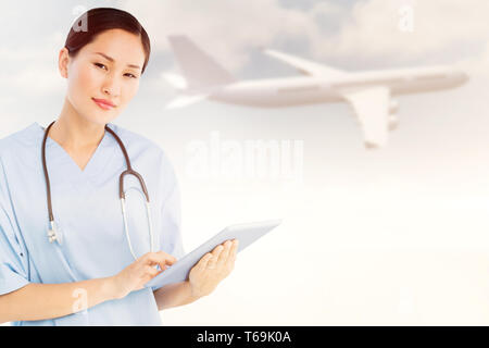 Composite image of surgeon using digital tablet with group around table in hospital Stock Photo