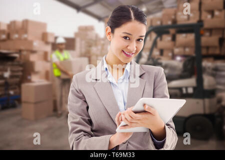Composite image of portrait of a smiling businesswoman using a tablet computer Stock Photo