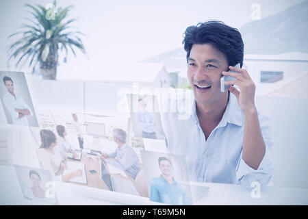 Composite image of smiling man using his laptop and talking on phone Stock Photo