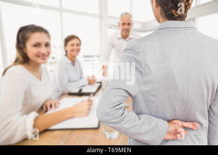 Composite image of businesswoman with fingers crossed behind her back over white background Stock Photo