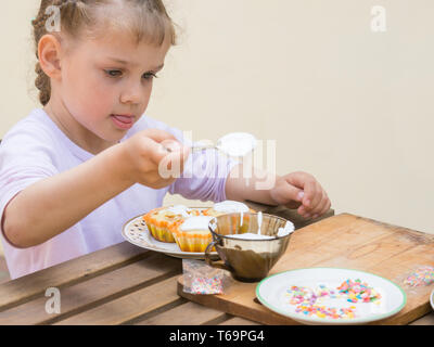Girl puts focus on confectionery glaze Easter cupcakes Stock Photo