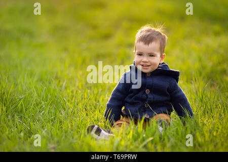 little boy sitting in the green grass Stock Photo