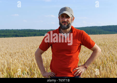 bearded man standing in a wheat field on sunny day Stock Photo