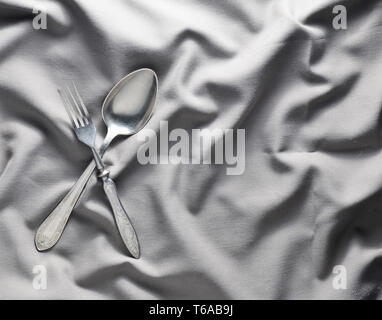 Spoon and fork on a gray silk tablecloth. Vintage cutlery. Copy space. Top view. Stock Photo