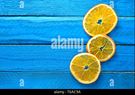 Slices of dried orange on blue wooden boards. Top view. Copy sace. Stock Photo