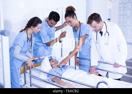 Doctors putting an oxygen mask on patient and adjusting iv drip Stock Photo