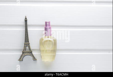 A bottle of French perfume and a statuette of the Eiffel Tower on a white wooden table. Top view. Stock Photo