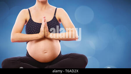 Composite image of pregnant woman sitting on exercise mat with hands joined Stock Photo