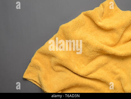 Yellow towel on a gray background. Copy space. Top view. Stock Photo