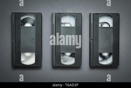 Three video cassettes on a gray background. Retro technology from the 80s. Top view. Stock Photo