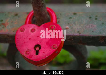 beautiful red heart-shaped padlock locked on iron chain Stock Photo