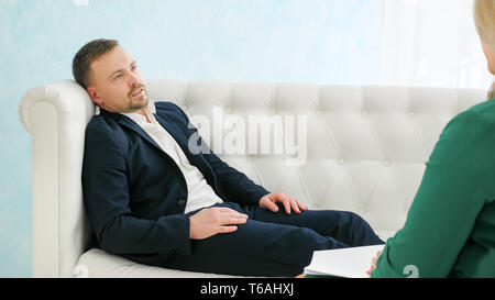 Upset man having consultation with female psychologist. Stock Photo