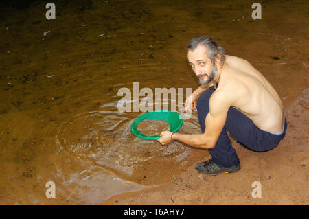 prospector panning gold in a river with sluice box Stock Photo