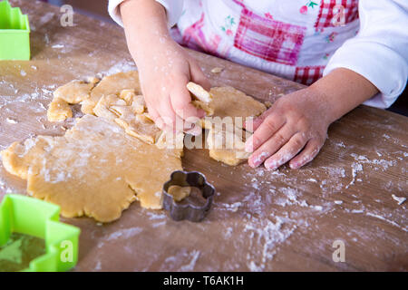 Child Chef preparing the dough. Closeup girl's chef's hands with dough and flour, food preparing process. Stock Photo