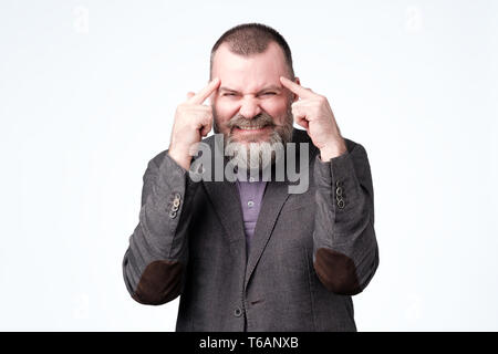 Man with a finger at the temple, hard to think and try to solve a serious problem, writhing in pain Stock Photo