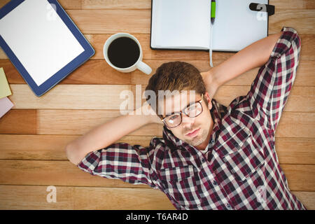 Composite image of hipster wearing eye glasses lying on hardwood floor Stock Photo