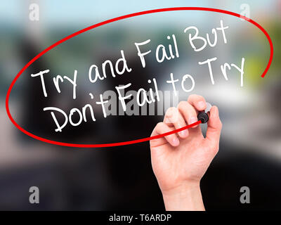 Man Hand writing Try and Fail But Don't Fail to Try with black marker on visual screen. Stock Photo