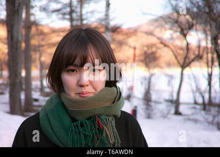A pretty Japanese lady posing in front of Winter scenery, with copy space on the right Stock Photo