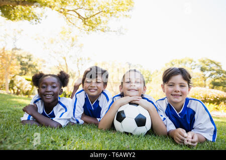 children soccer team smiling at camera while lying on the floor Stock Photo