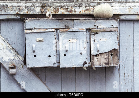 three very old and grungy mailboxes at a gate Stock Photo
