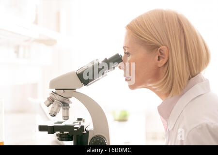 Woman looking through microscope Stock Photo