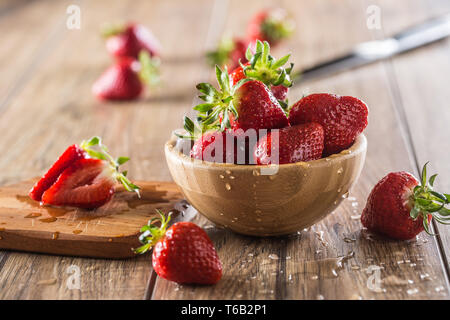 Juicy washed strawberries in wooden bowl on kitchen table Stock Photo
