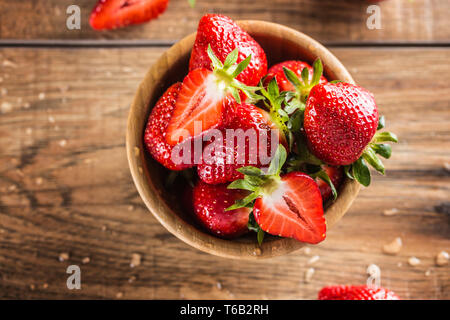 Juicy washed strawberries in wooden bowl on kitchen table Stock Photo
