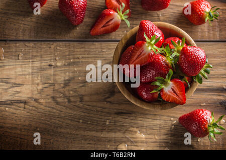Juicy washed strawberries in wooden bowl on kitchen table Stock Photo
