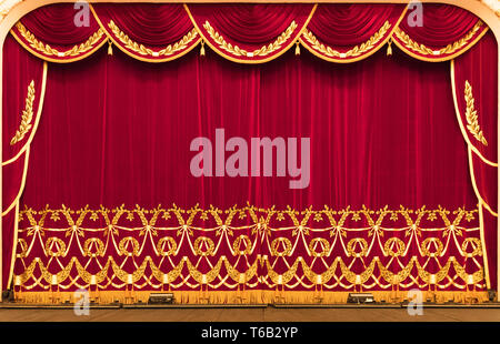 A theatrical curtain of red color embroidered with a golden cloth. Presentation. Cinema. Stock Photo