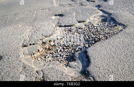 Large hole in the asphalt road. Open pit road for cars close-up Stock Photo