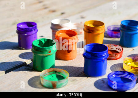 small gouache paint cans stand on a wooden table Stock Photo
