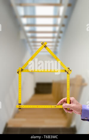 shell of house under construction with folding ruler in hand of real estate agent Stock Photo