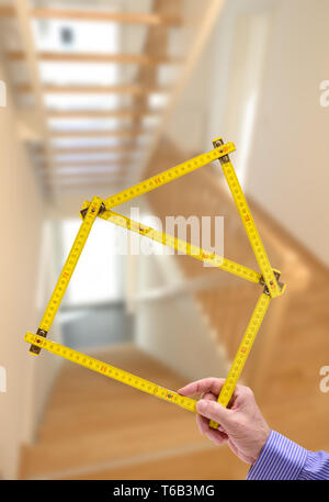 shell of house under construction with folding ruler in hand of real estate agent Stock Photo