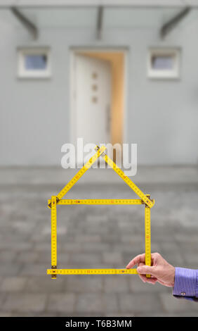 shell of house under construction with folding ruler in hand of real estate agent Stock Photo