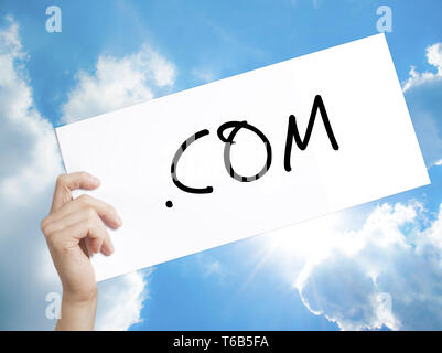 .COM Sign on white paper. Man Hand Holding Paper with text. Isolated on sky background.  Business concept. Stock Photo Stock Photo