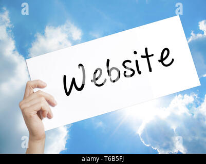 Website Sign on white paper. Man Hand Holding Paper with text. Isolated on sky background Stock Photo
