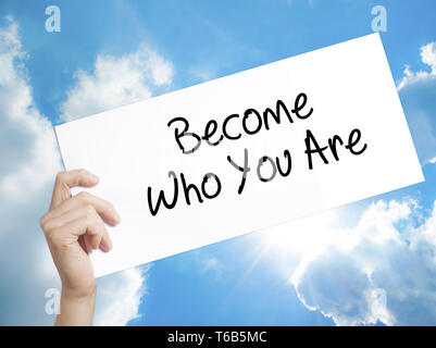 Become Who You Are Sign on white paper. Man Hand Holding Paper with text. Isolated on sky background Stock Photo