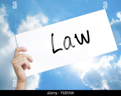 Law Sign on white paper. Man Hand Holding Paper with text. Isolated on sky background Stock Photo