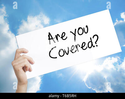 Are you Covered? Sign on white paper. Man Hand Holding Paper with text. Isolated on sky background Stock Photo